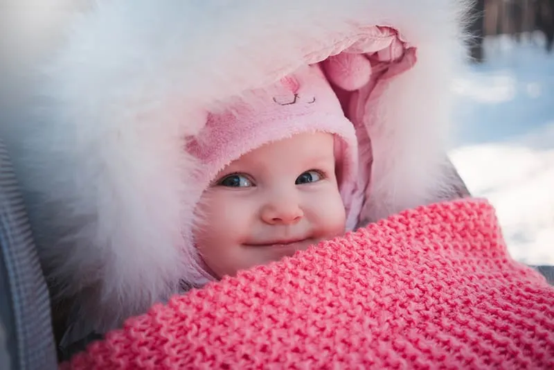 süßes Baby Mädchen in Winterjacke und Hut lächelnd