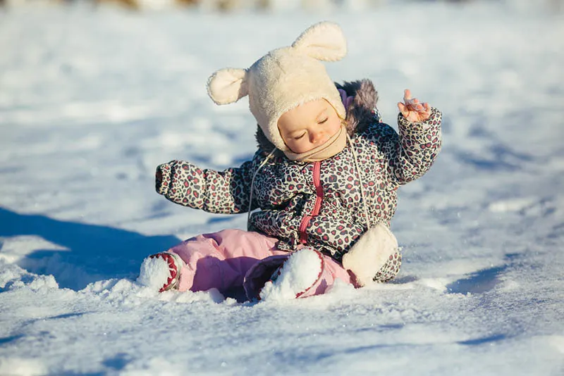 süßes Baby Mädchen spielen auf dem Schnee