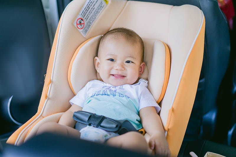 süßes Baby lächelnd im Autositz