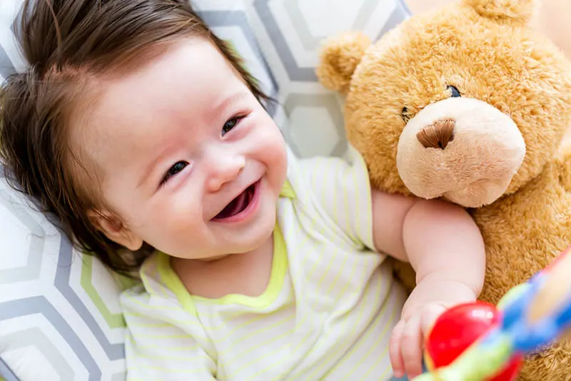 süßes Baby lächelnd und liegend mit Teddybär