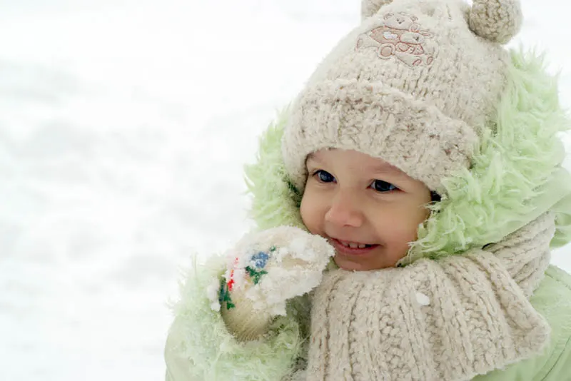süßes kleines Mädchen in Winterkleidung essen Schnee