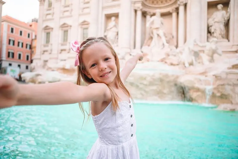 süßes kleines Mädchen posiert vor Brunnen in Rom
