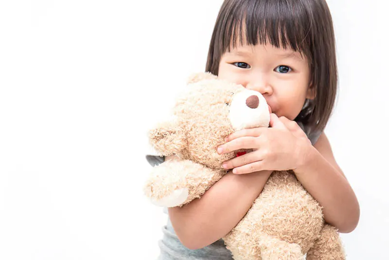 süßes kleines Mädchen umarmt Teddybär