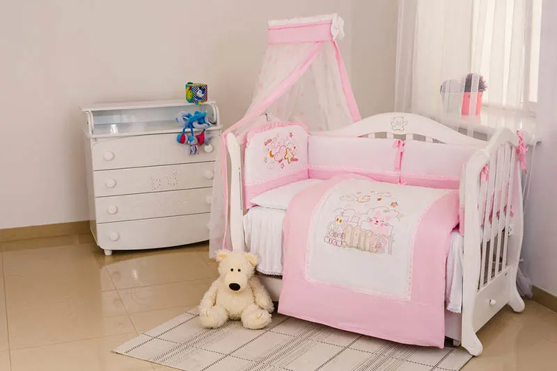 süßes rosa Babybett im Schlafzimmer mit Spielzeug