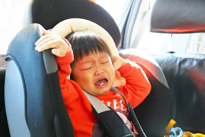 trauriges Baby Junge sitzt in einem Autositz und weint