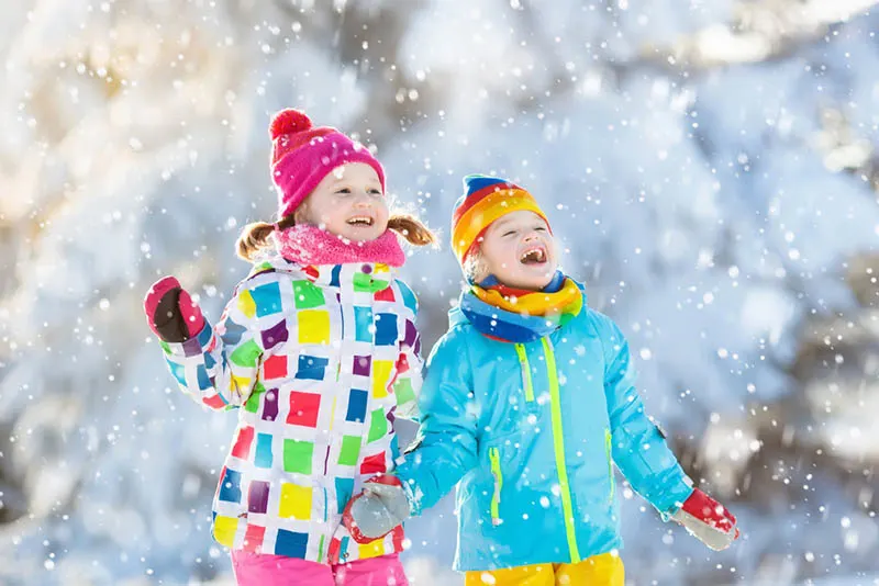 zwei kleine Mädchen, die den Schnee im Freien genießen