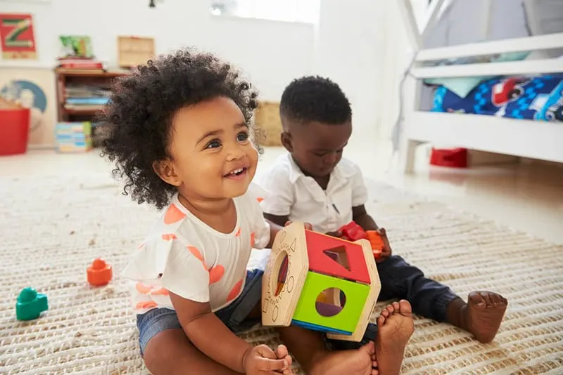 Baby Junge und Mädchen spielen mit Spielzeug im Spielzimmer zusammen