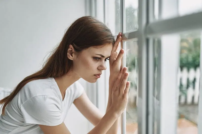 Depressive junge Frau lehnt sich an das Fenster
