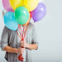 junger Mann mit Geburtstagsballons