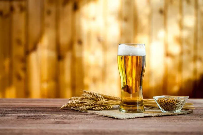 Glas Bier mit Weizen auf einem Holztisch