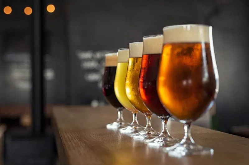 Gläser mit verschiedenen Sorten Craft-Bier auf Holzbar