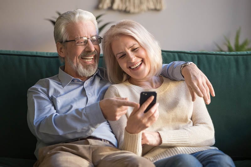 Glückliches älteres altes Paar hält Smartphone