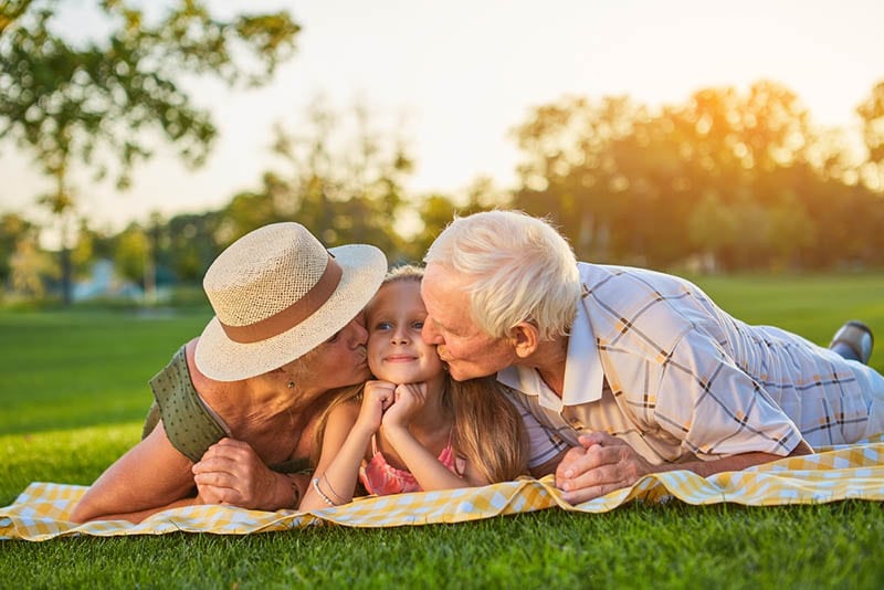 Großeltern küssen Enkelin im Park