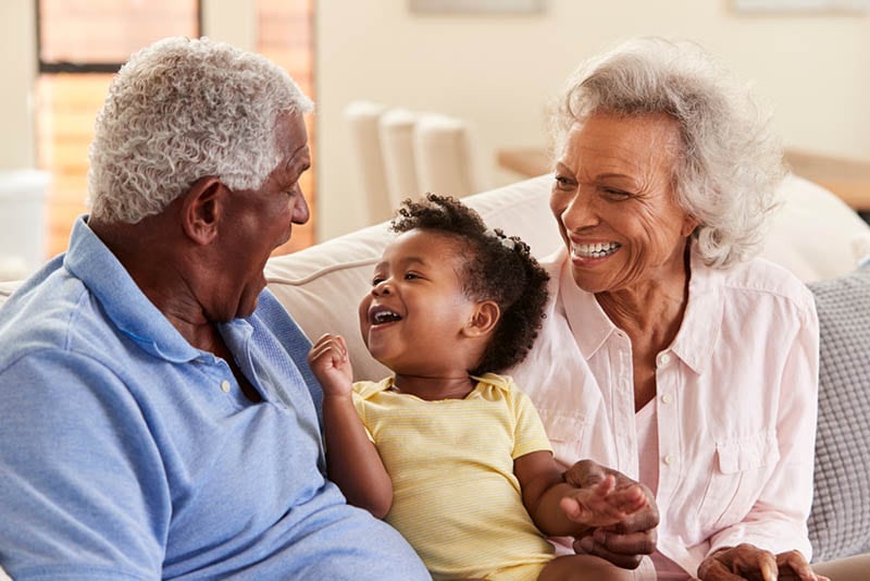 Großeltern lächelnd mit niedlichen kleinen Enkelin auf der Couch