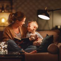 Junge Mutter liest ihrem Sohn auf der Couch ein Buch vor