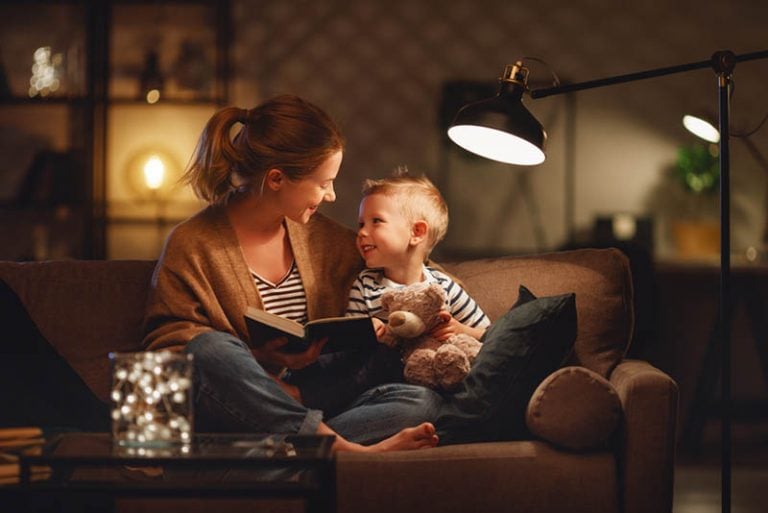 Junge Mutter liest ihrem Sohn auf der Couch ein Buch vor