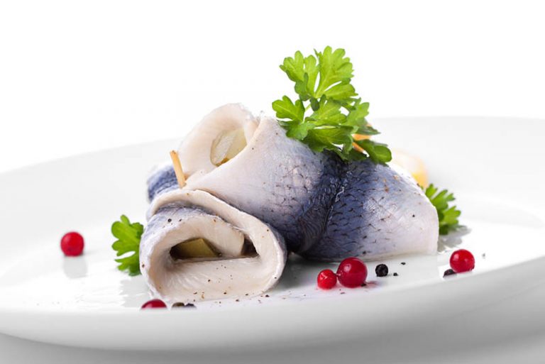 marinierter frischer Rollmops mit Gewürzen auf Teller