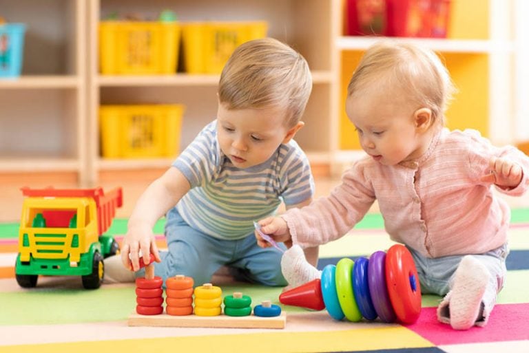 süße Babys spielen mit Spielzeug auf dem Boden