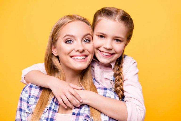 ein kleines Mädchen und ihre Tante posieren vor einem gelben Hintergrund