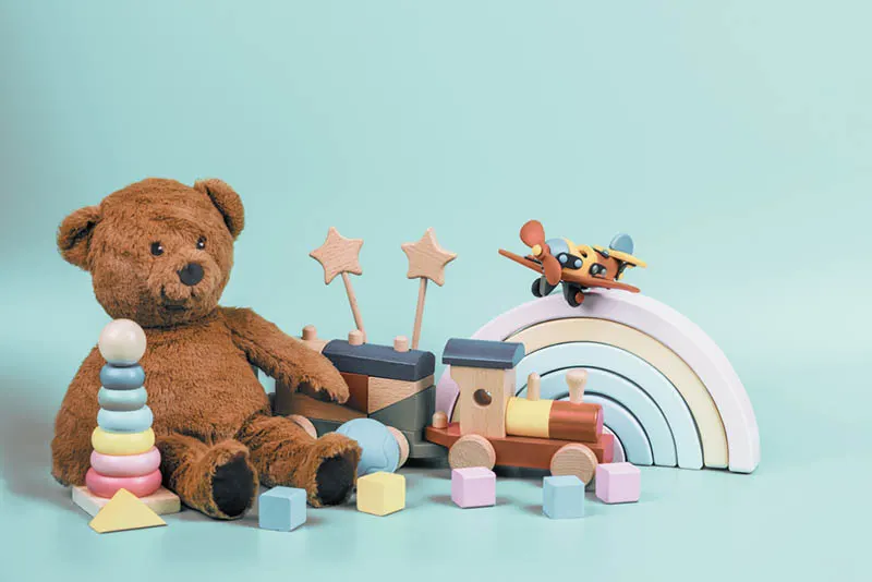 Teddybär und Holzspielzeug auf dem blauen Boden