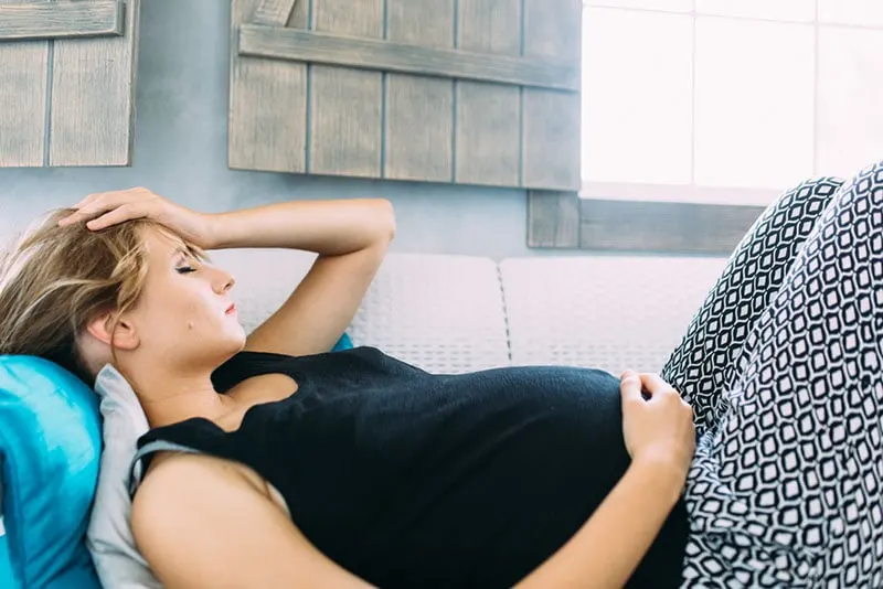 besorgte schwangere Frau, die auf der Couch liegt