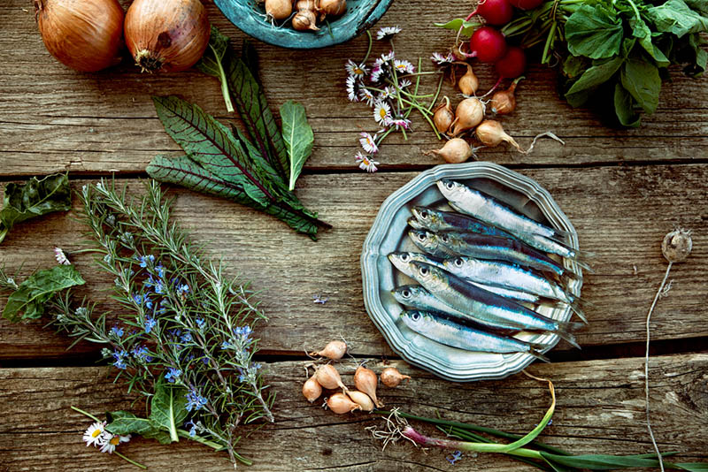 blauer Fisch auf dem Teller mit Gemüse auf Holztisch