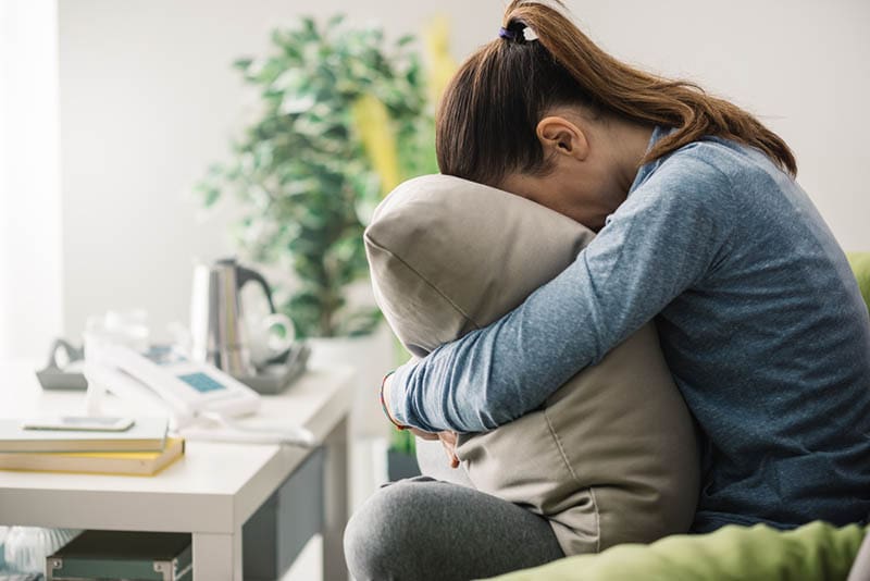 gestresste Frau umarmt Kissen zu Hause