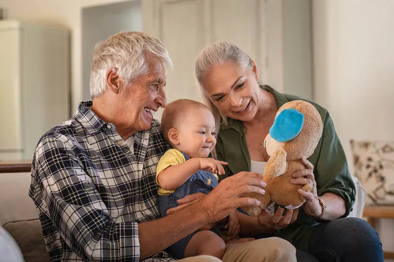 glückliche Großeltern spielen mit Enkel auf der Couch