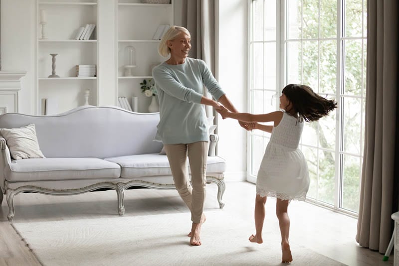 glückliche Großmutter und Enkelin tanzen zu Hause