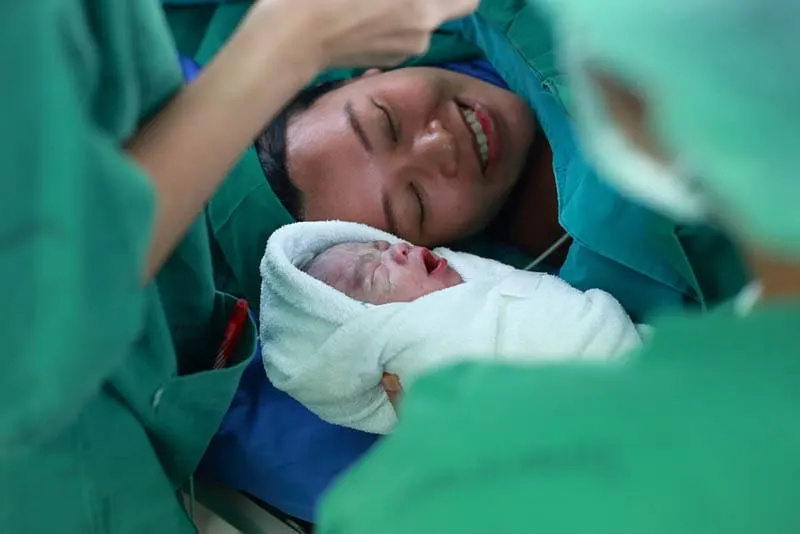 glückliche Mutter in den Wehen mit ihrem neugeborenen Baby