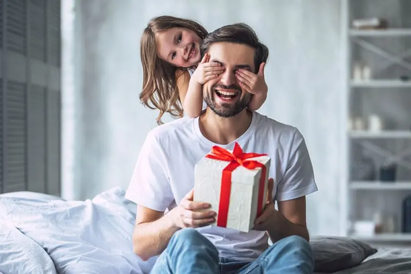 süßes kleines Mädchen überrascht ihren Vater mit Geschenk