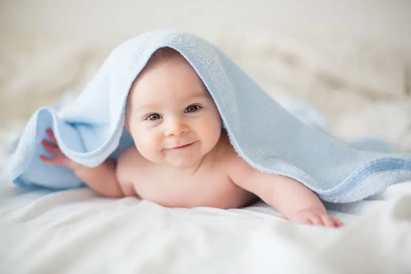 Baby Junge entspannt nach der Dusche mit blauen Handtuch bedeckt