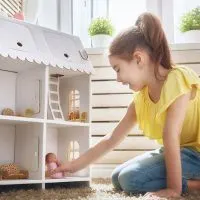 Süßes kleines Mädchen spielt mit einem Puppenhaus