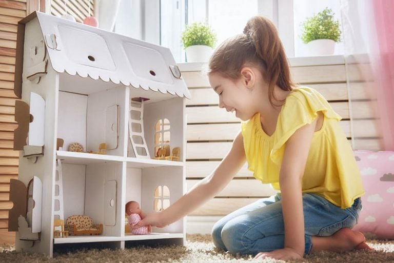 Süßes kleines Mädchen spielt mit einem Puppenhaus
