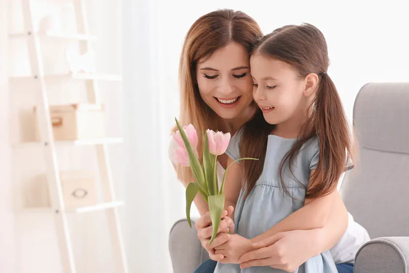 Junge Mutter gibt Blumen zu ihrer süßen Tochter