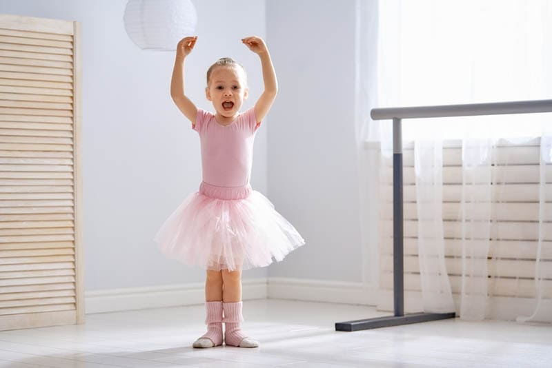 Mädchen in einem rosa Tutu tanzt in einem Raum als Ballerina