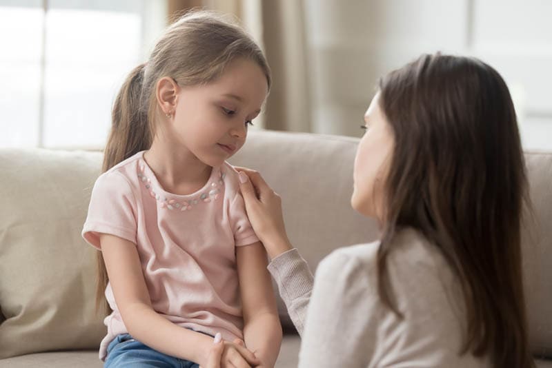 Mutter spricht mit trauriger kleiner Tochter zu Hause