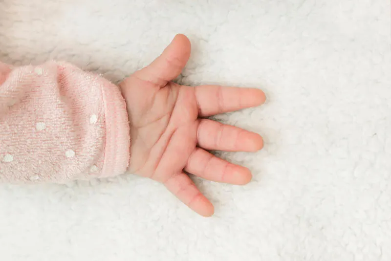 Neugeborenes Baby Hand auf dem Bett