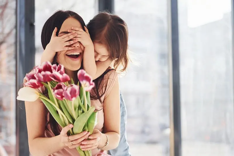 Tochter gratuliert Mutter Geburtstag und gibt Blumenstrauß
