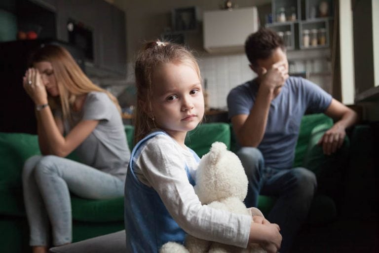 kleines Mädchen hält ein Spielzeug, während ihre Eltern durch eine Trennung gehen