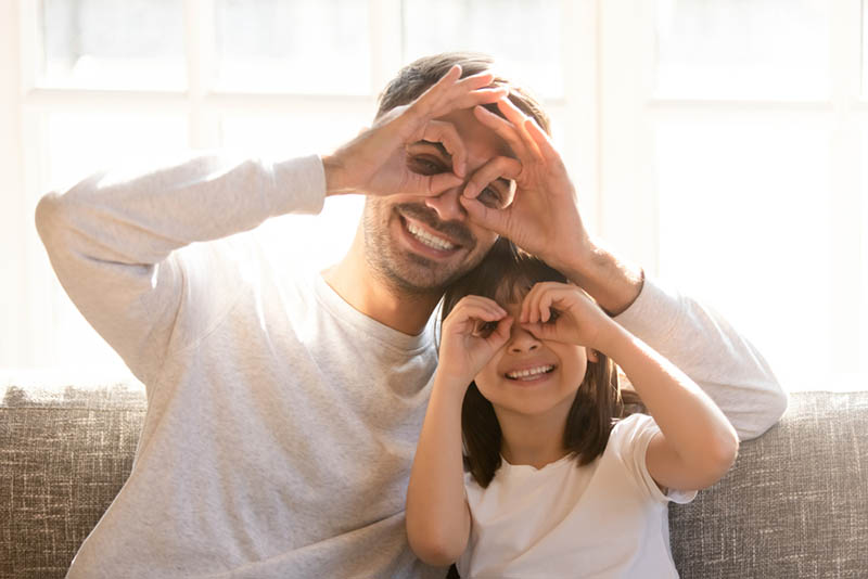 Vater und liebenswert Tochter tun lustige Gesichter mit Fingern