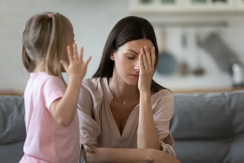 depressive Mutter reibt sich das Gesicht, als ihre Tochter versucht, mit ihr zu sprechen