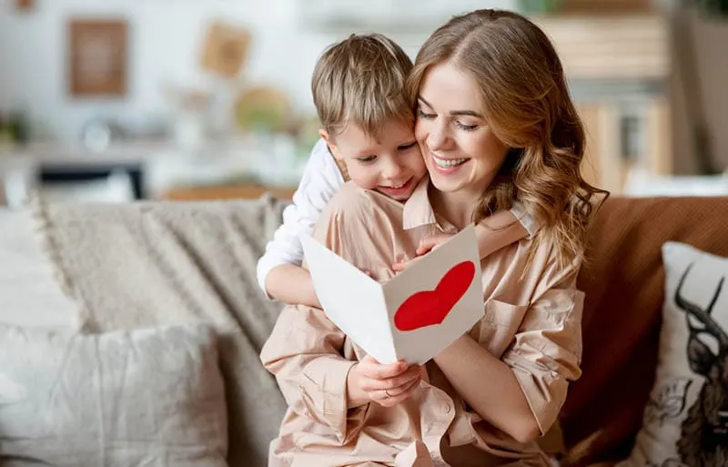glückliche Mutter umarmt Sohn und Lesen Brief für Geburtstag