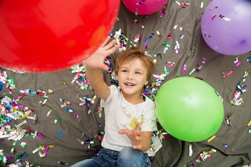 glücklicher Junge spielt mit Luftballons
