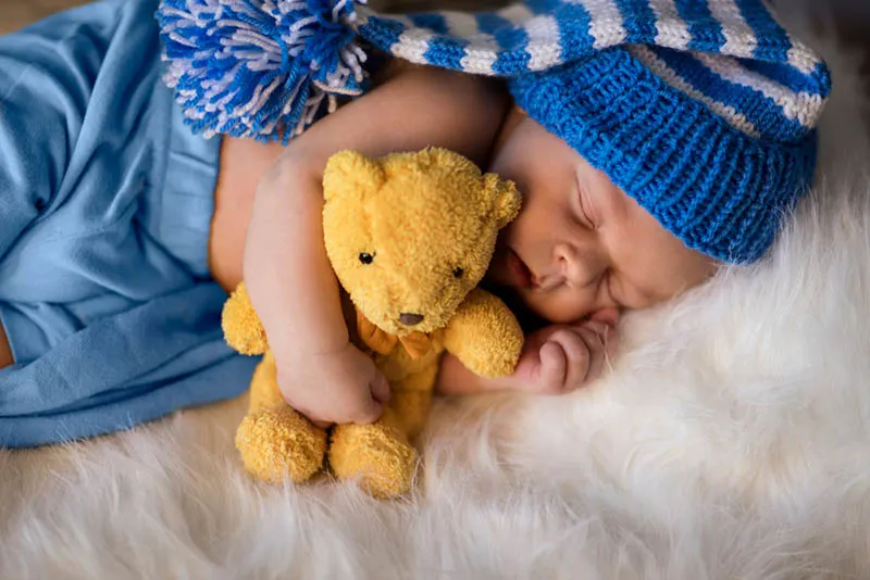 kleine neugeborene Junge umarmt Teddybär und schlafen