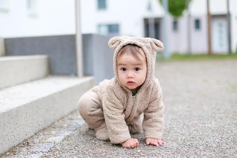 kleiner Baby-Junge im Teddybär-Kostüm im Freien