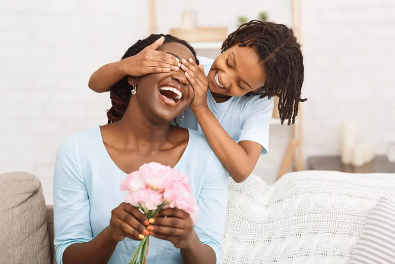 kleines Mädchen überrascht ihre Mutter mit Blumen