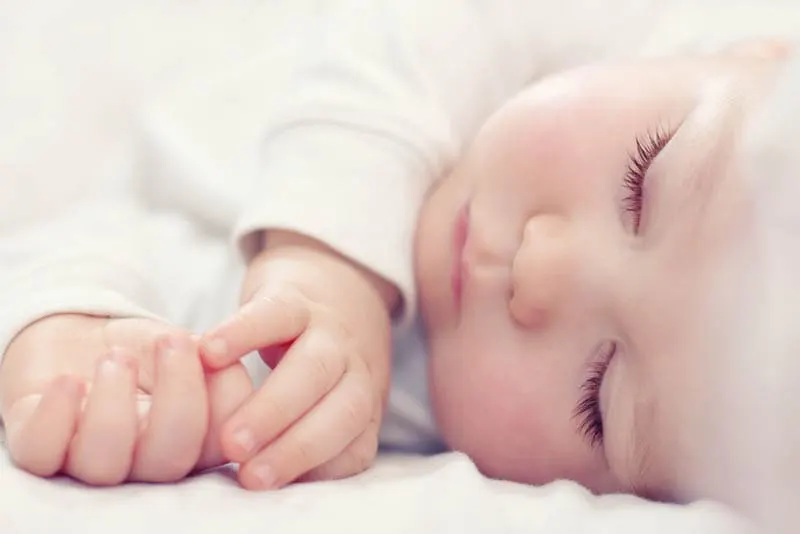 schönes Baby mit langen Wimpern schlafend im Bett