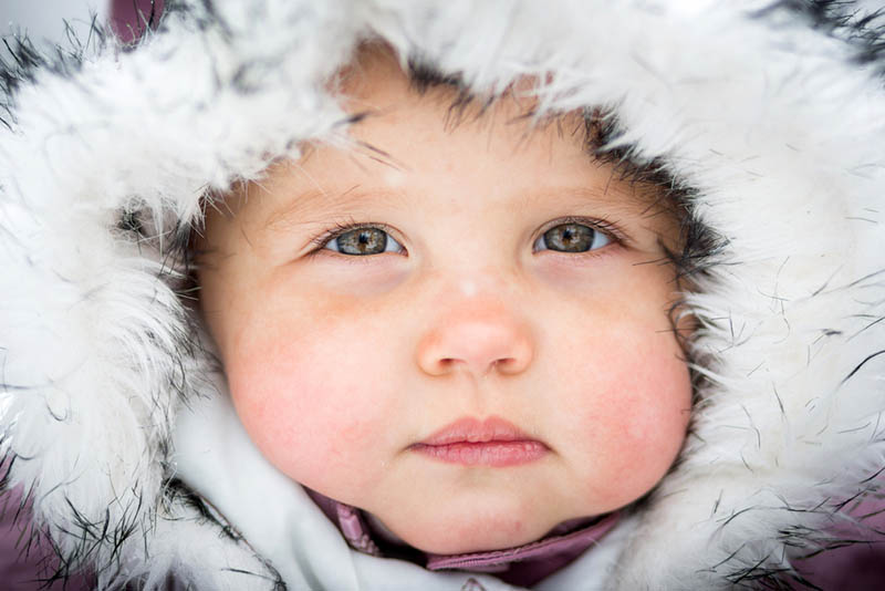 süßes Baby Junge mit dicken Wangen trägt Wintermütze