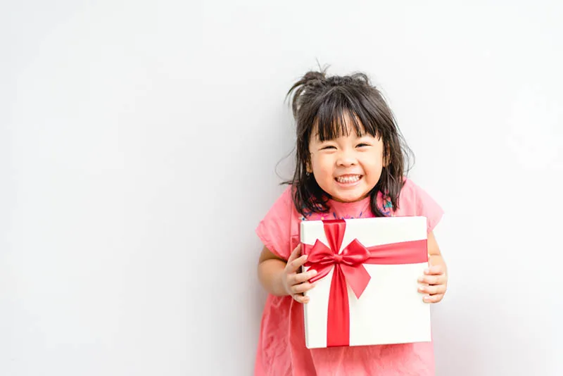 süßes kleines Mädchen lächelnd, während ein Geschenk halten